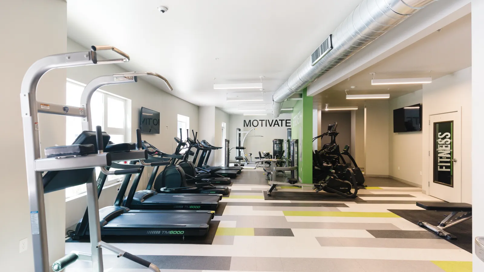 Modern gym interior featuring treadmills, ellipticals, and motivational signage.