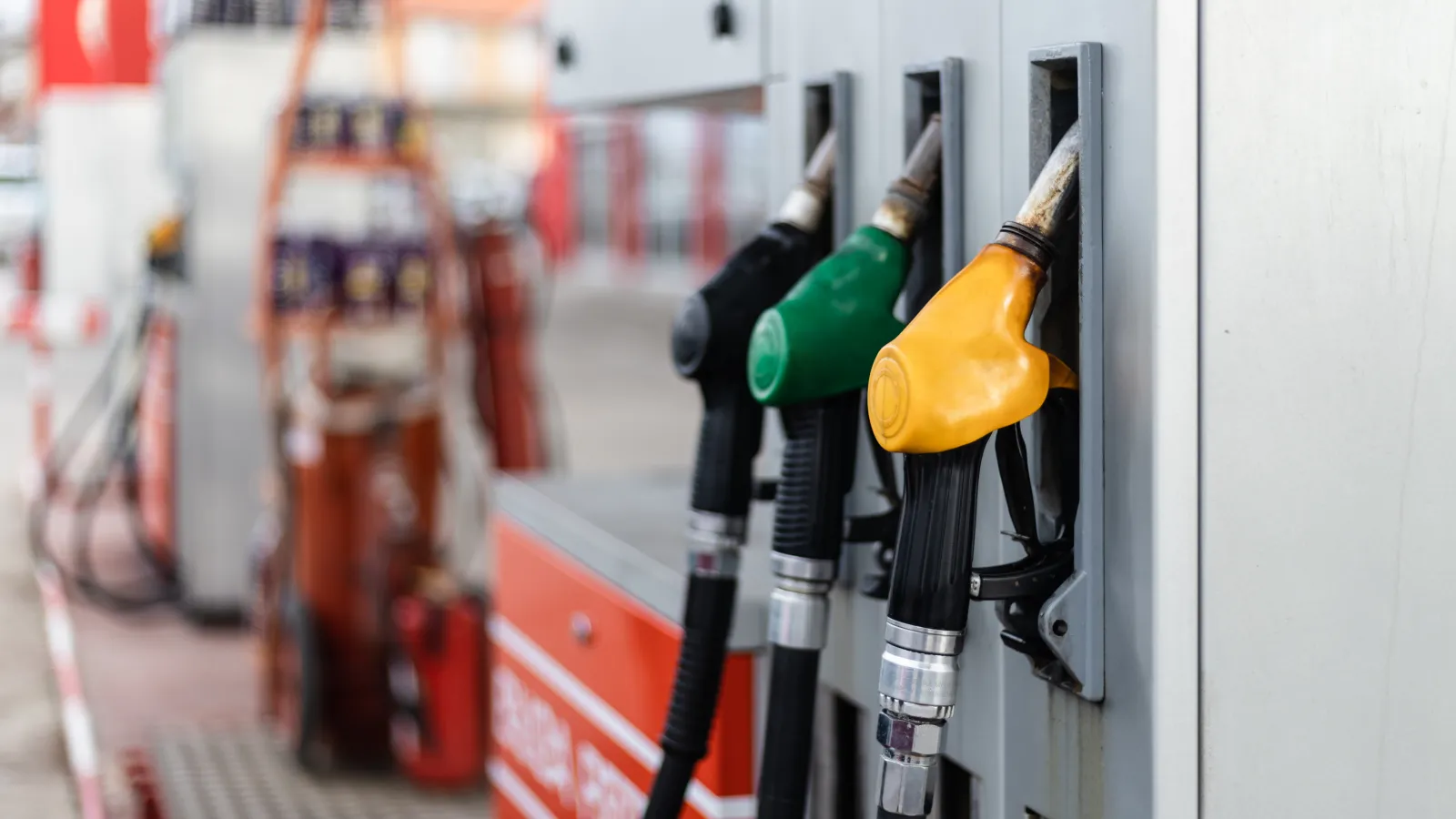 Close-up of fuel pump nozzles in yellow, green, and black at a gas station dispenser.