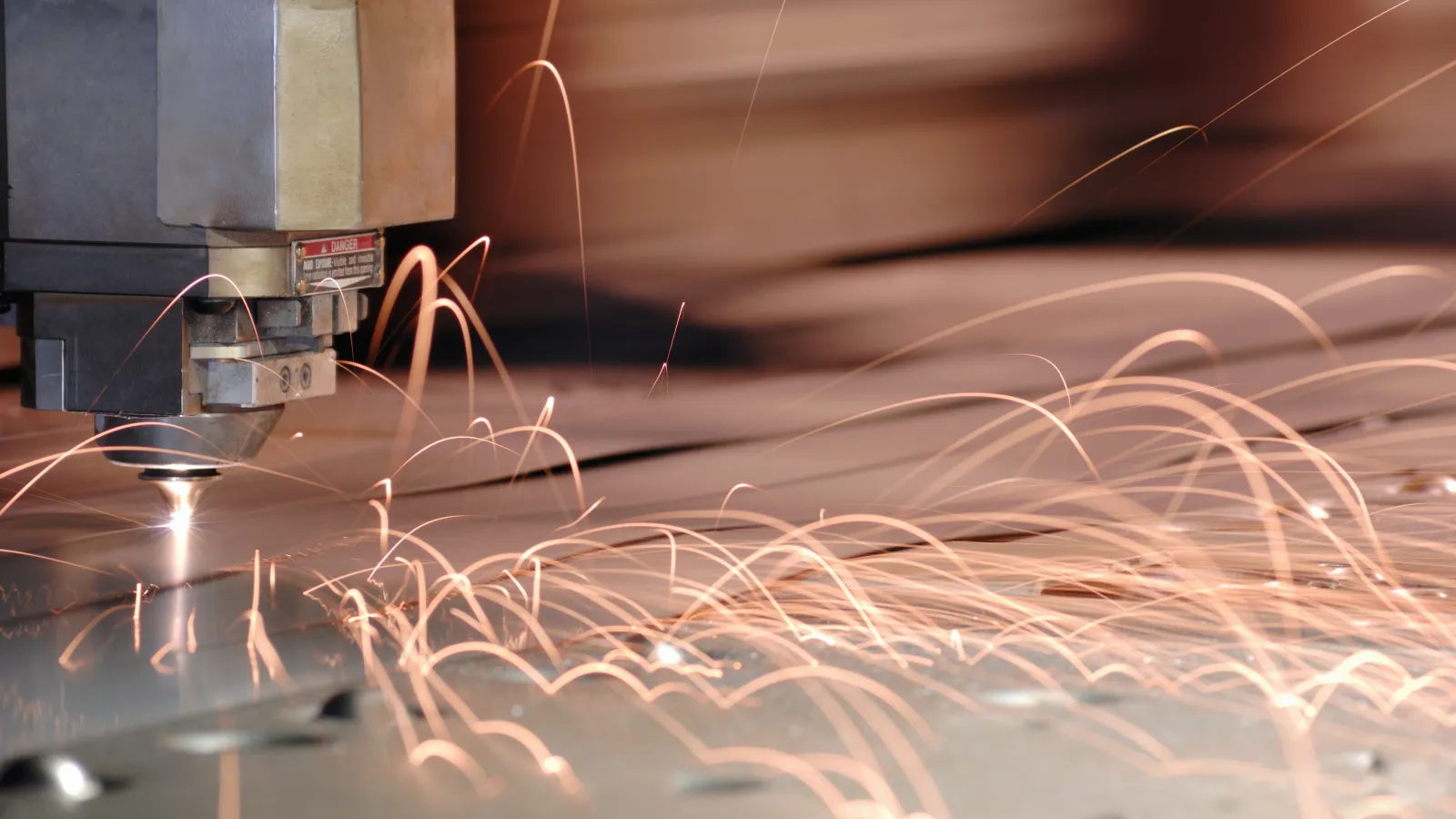 Laser cutting metal with sparks flying in an industrial setting.