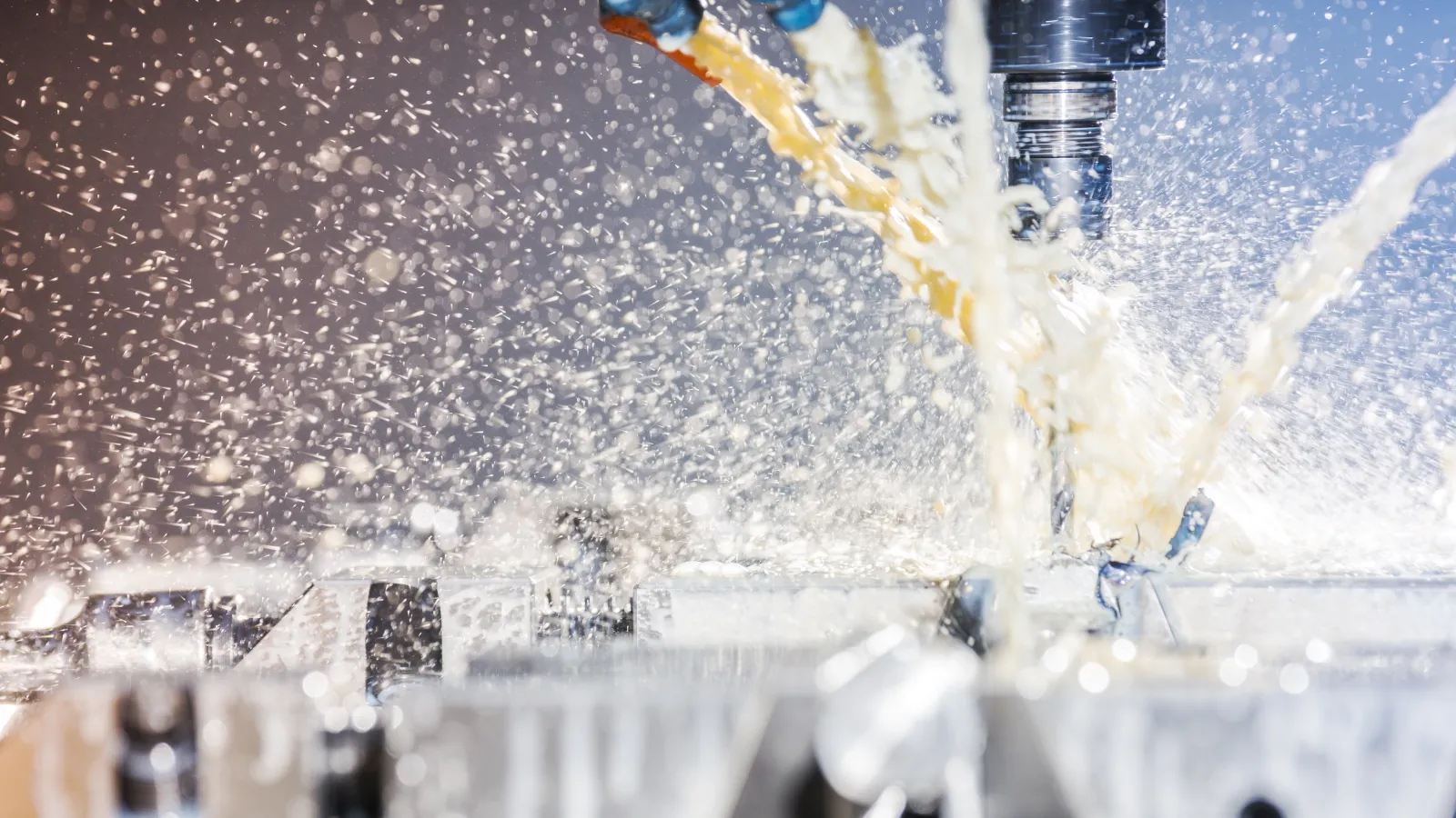 Close-up of CNC milling machine with coolant fluid spraying during metal cutting process