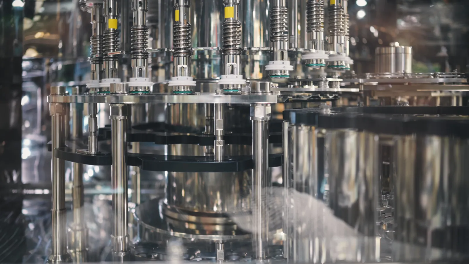 Close-up of stainless steel machinery components in a modern industrial production line with spring mechanisms.