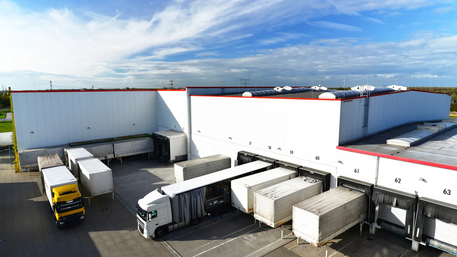 Aerial view of a logistics facility with trucks unloading goods at the loading docks.