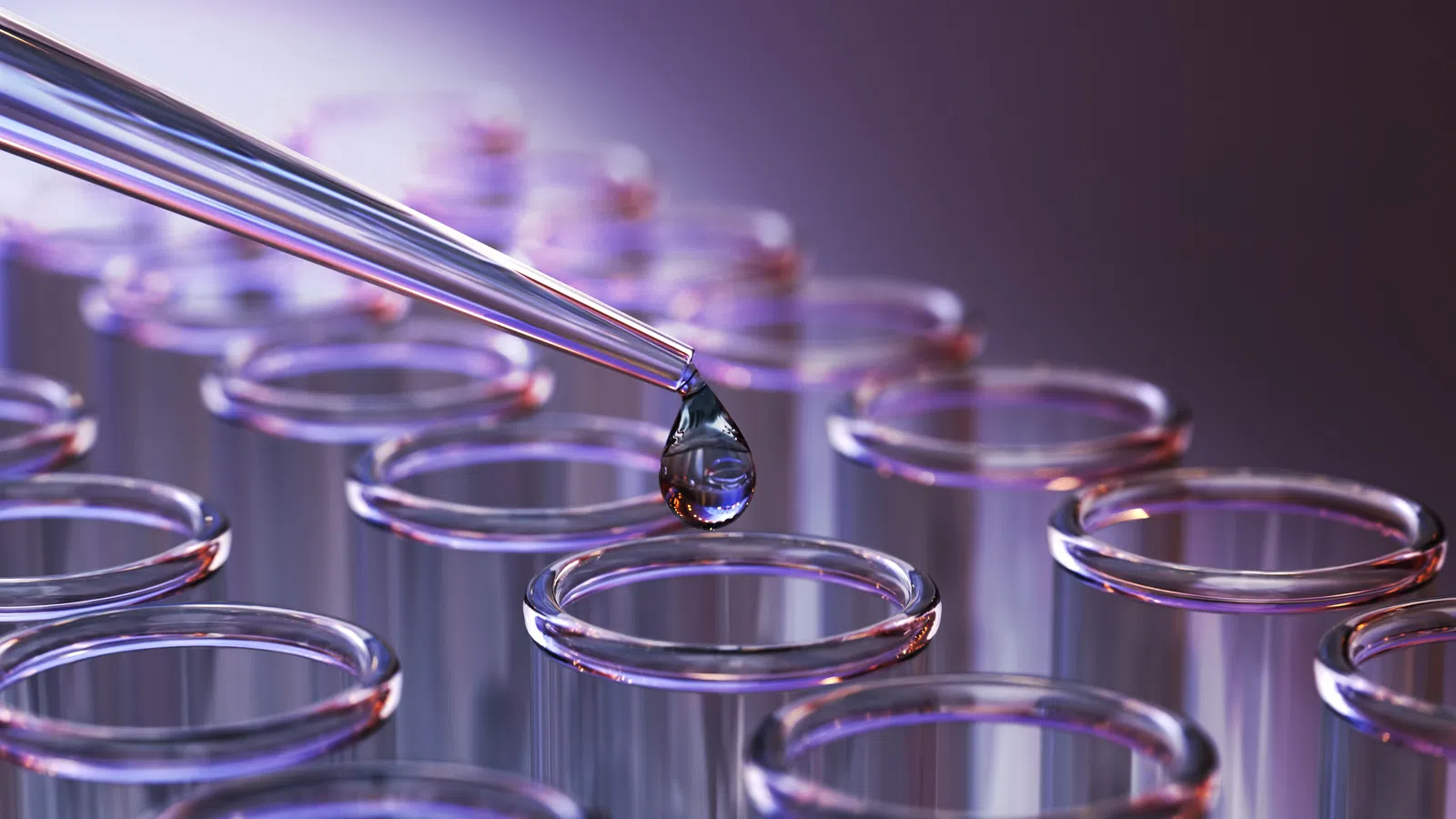 Close-up of pipette dropping liquid into a test tube among rows of glass test tubes in a lab setting.