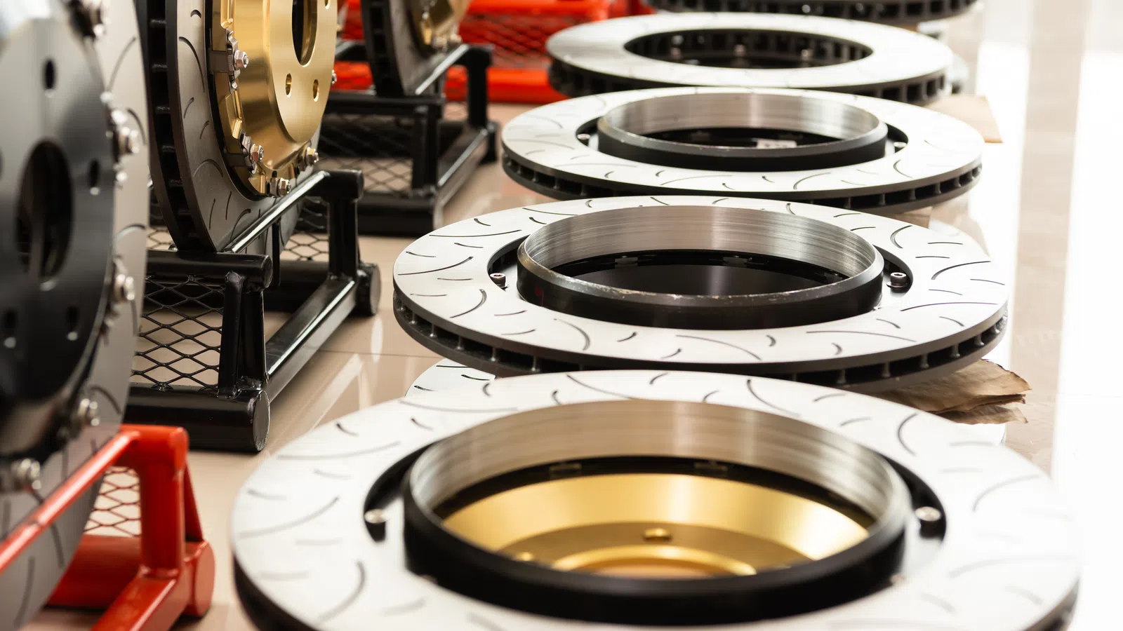 Close-up of polished brake rotors with gold and black centers arranged in a row on a floor.