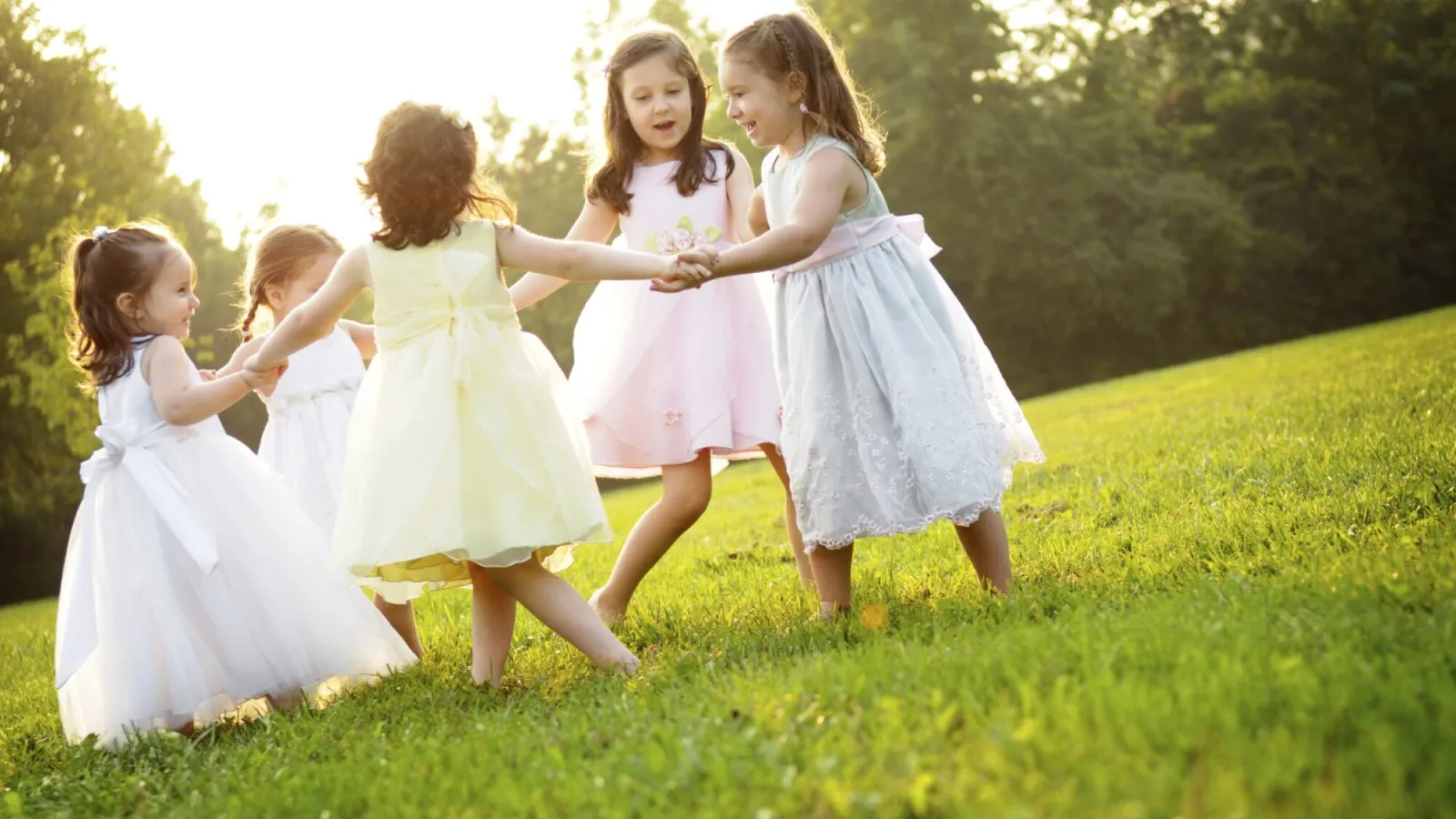 a group of girls in dresses running on grass