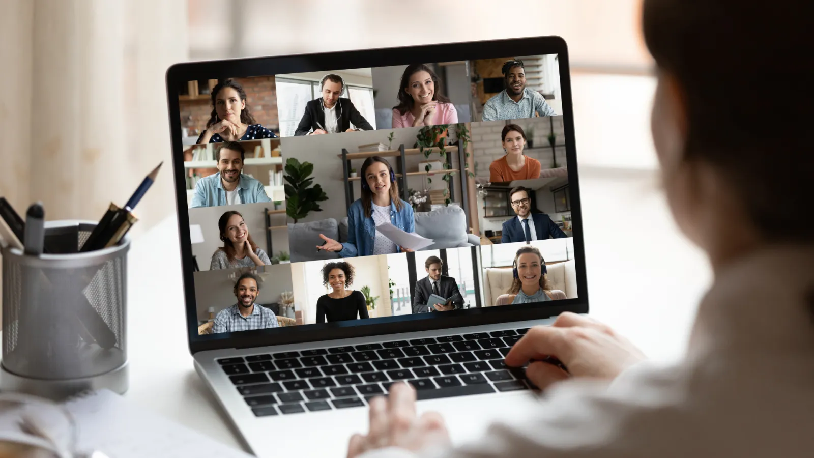 Person participating in a virtual meeting with diverse team members on a laptop screen in a home office.
