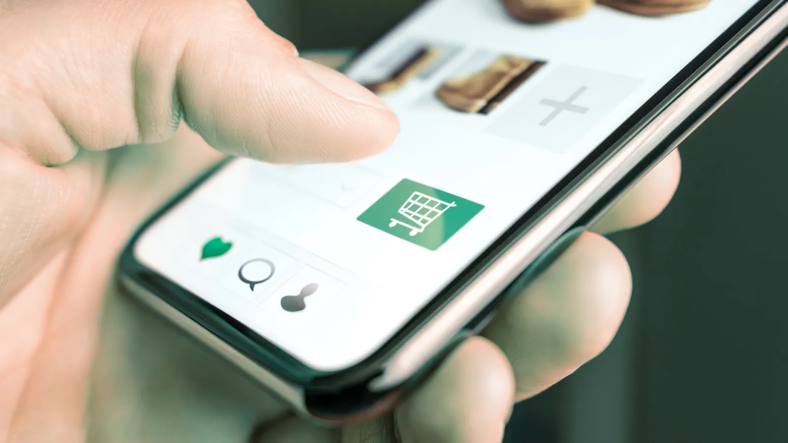Close-up of hand using smartphone to tap the shopping cart icon on an online shopping app