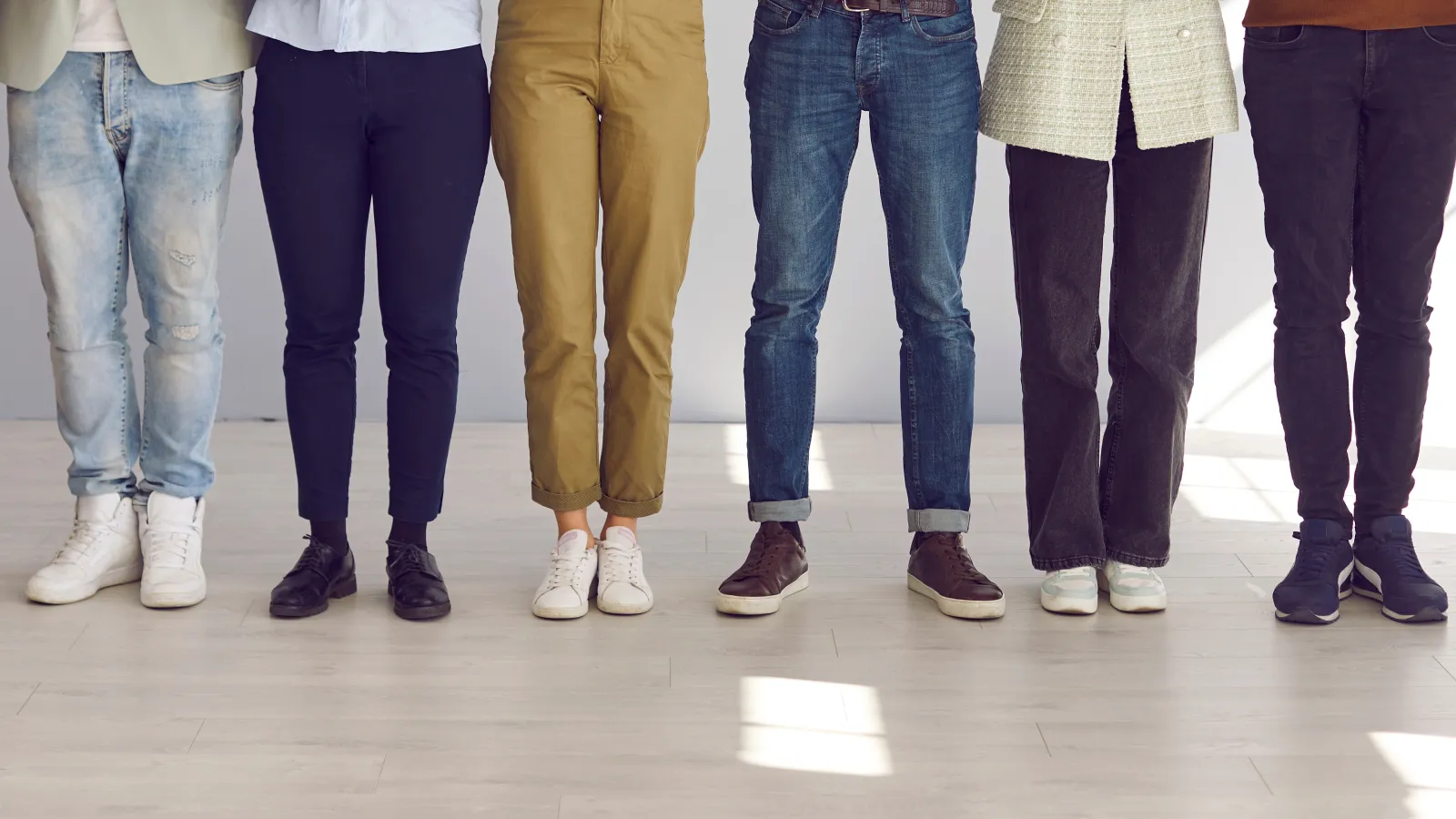 Diverse group of people standing in a row showing only their legs and footwear in casual and formal wear.
