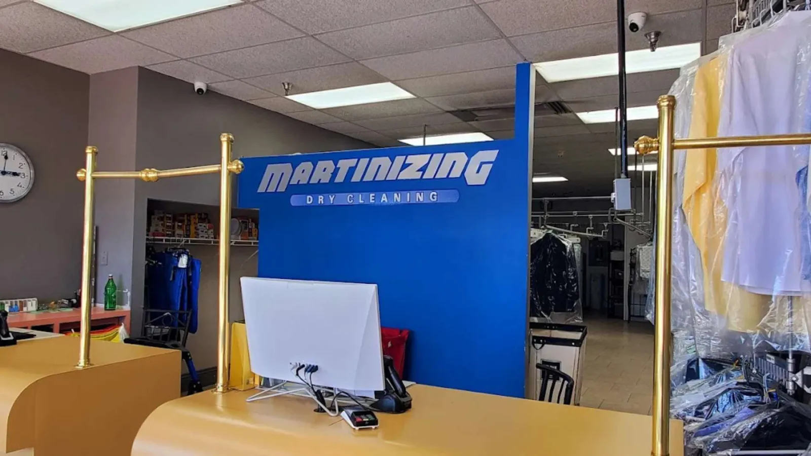Reception area of Martinizing Dry Cleaning with computer, counter, and clothes hanging in plastic covers
