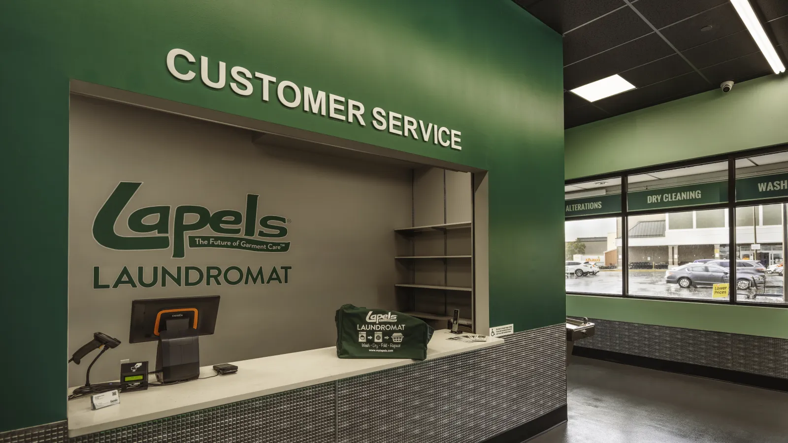 Customer service counter at Lapels Laundromat with branded bag and green interior walls.