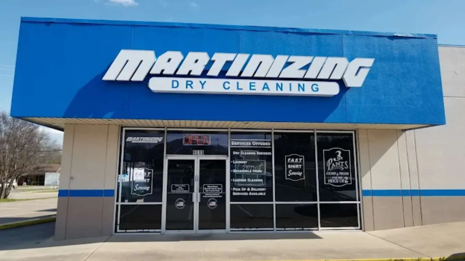 Front view of Martinizing Dry Cleaning storefront with blue signage and glass doors displaying services and promotions.