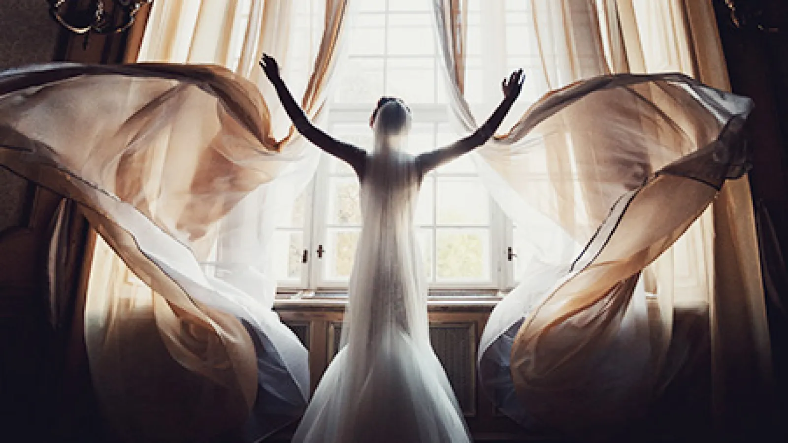 a woman in a wedding dress standing in front of a window