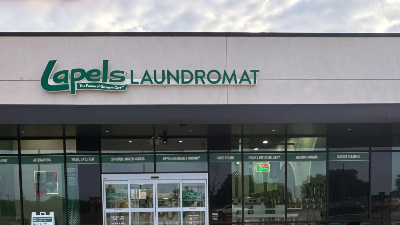 Exterior view of Lapels Laundromat storefront with multiple parking spaces and clear glass doors.