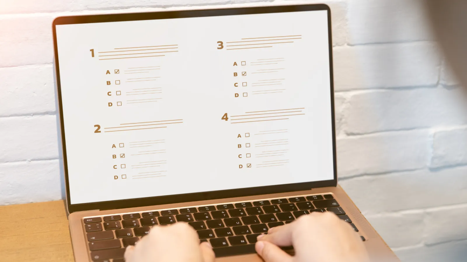 Person taking an online multiple-choice exam on a laptop with four questions displayed on screen.