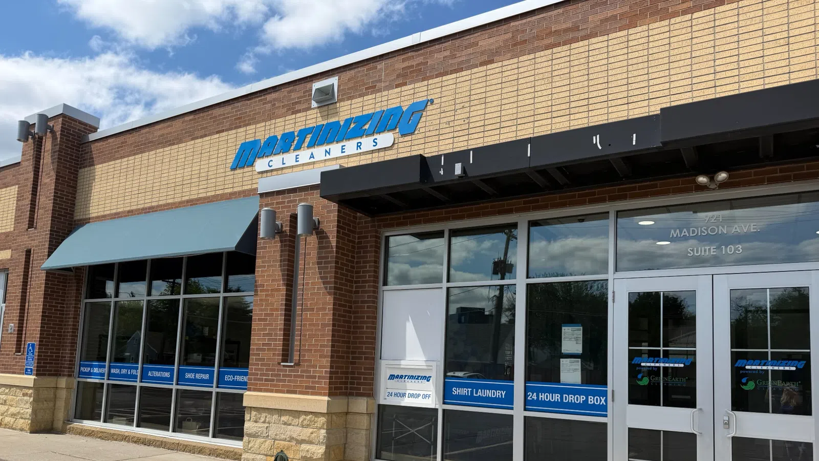 Exterior of Martinizing Cleaners storefront with signage, glass windows, and 24-hour drop box visible under sunny sky.