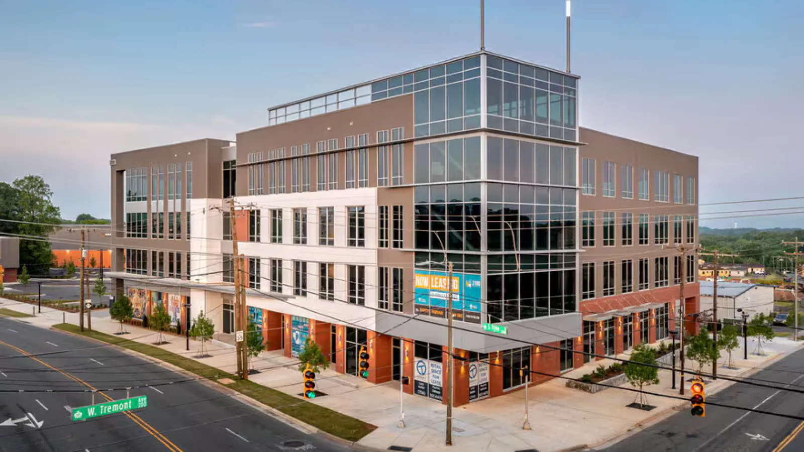 Modern four-story office building with large glass windows at the corner of a city street intersection