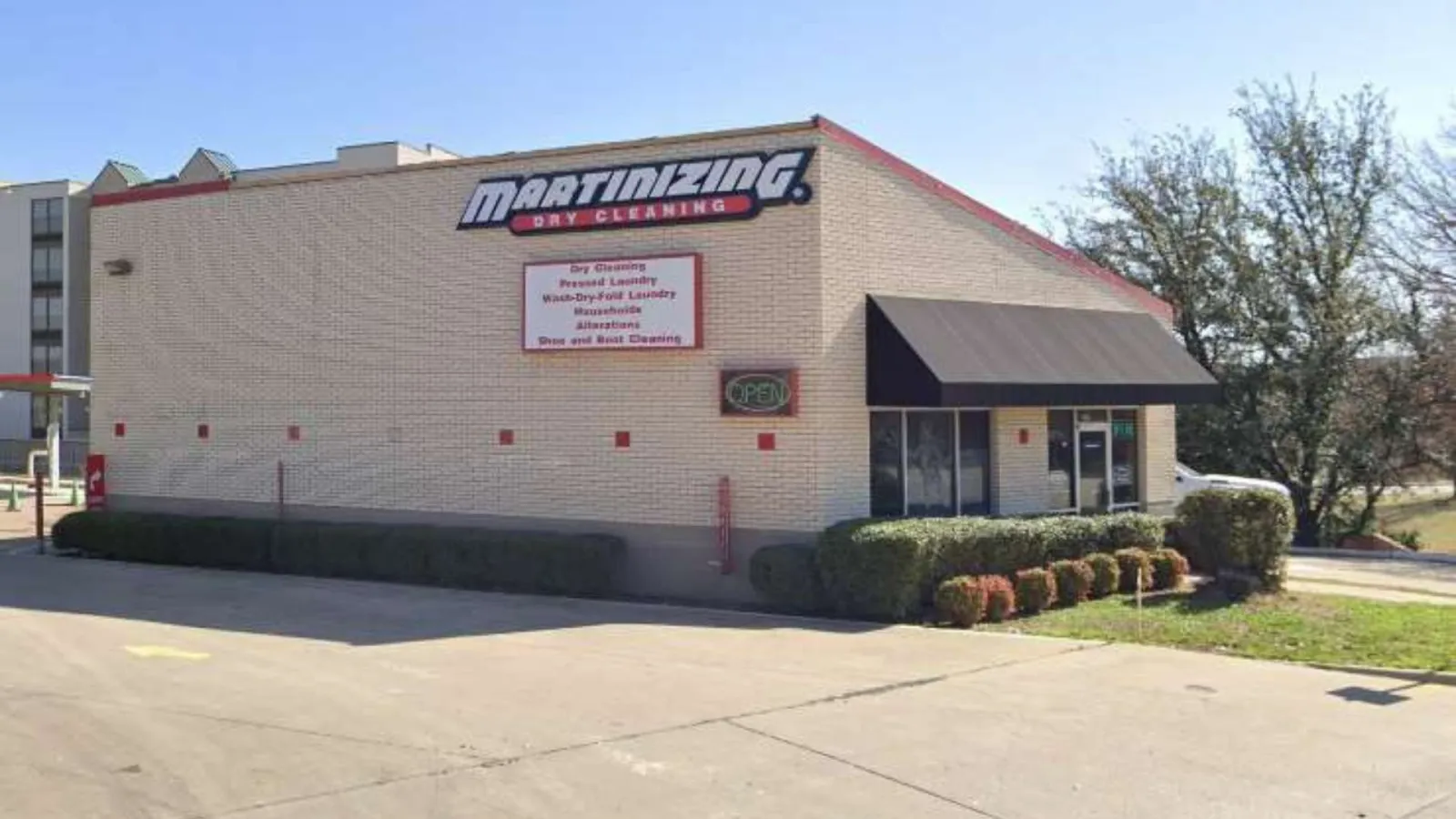 Martinizing Dry Cleaning building with clear signage and black awning on a sunny day