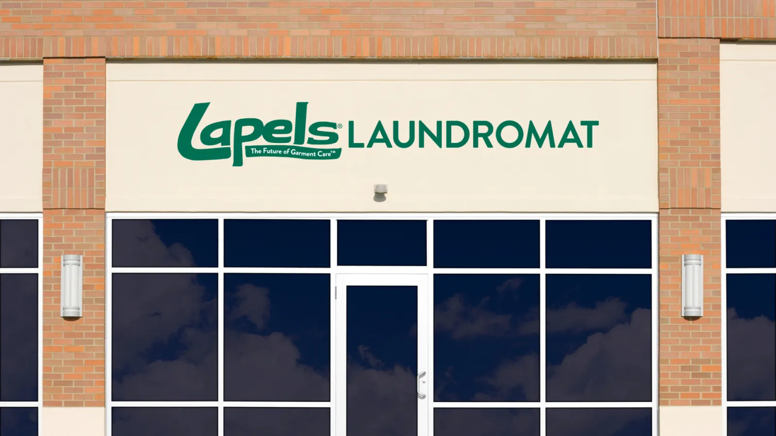 Exterior view of Lapels Laundromat with green signage on beige building and reflective glass windows.