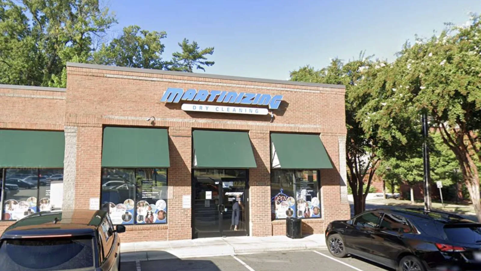 Martinizing Dry Cleaning storefront with green awnings and parked cars outside on a clear day
