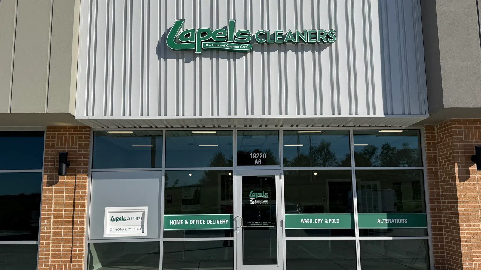 Front view of Lapels Cleaners storefront with signage displaying services like home delivery and alterations.