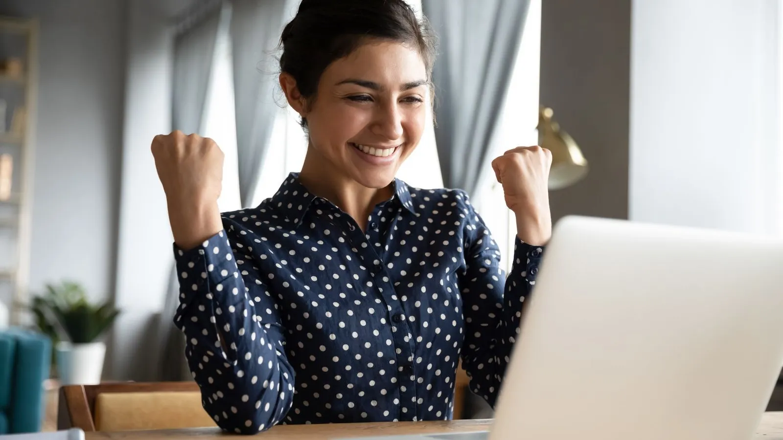 a woman smiling and pointing at a laptop