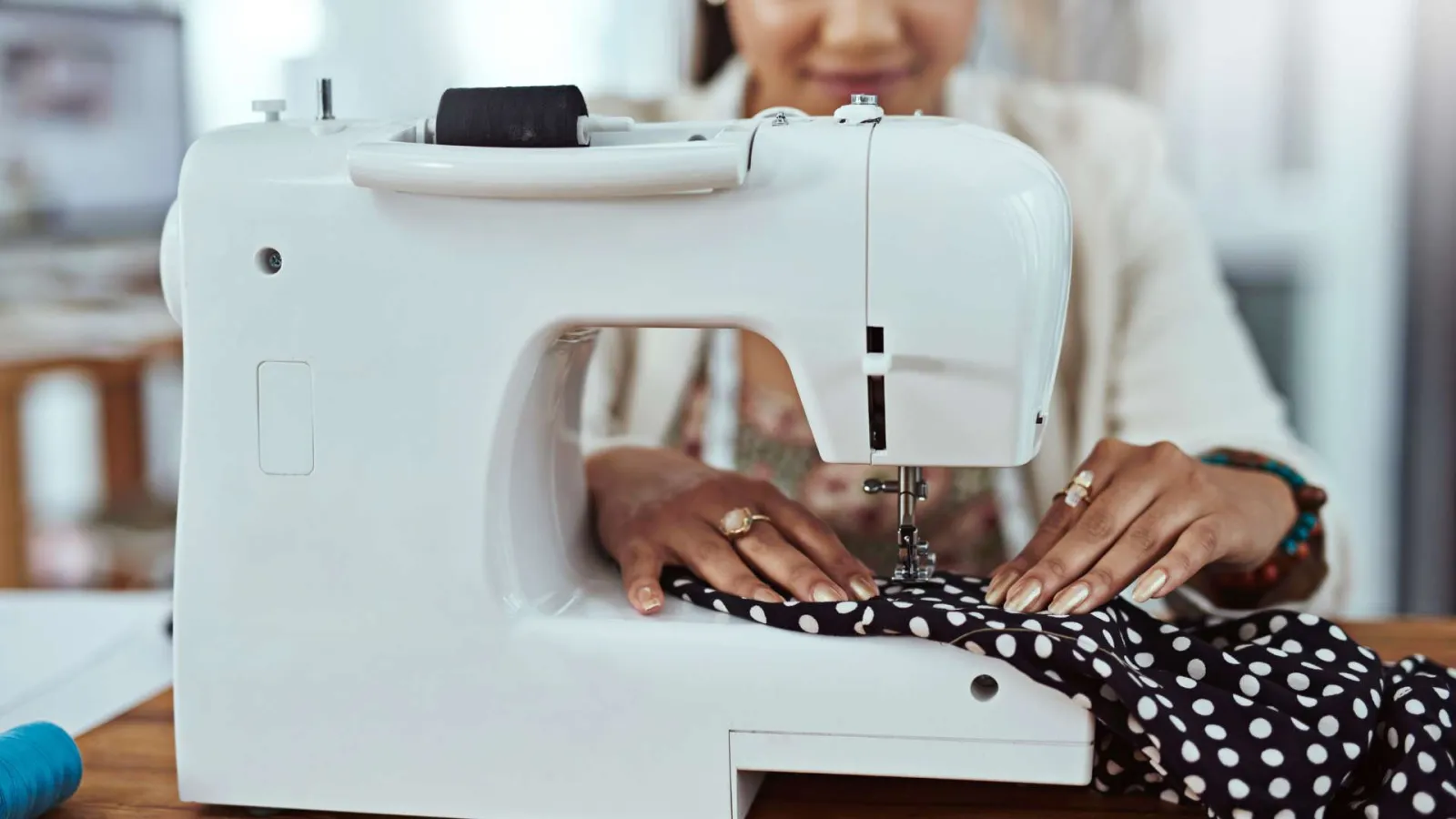 Close-up of a person sewing black and white polka dot fabric on a white sewing machine.