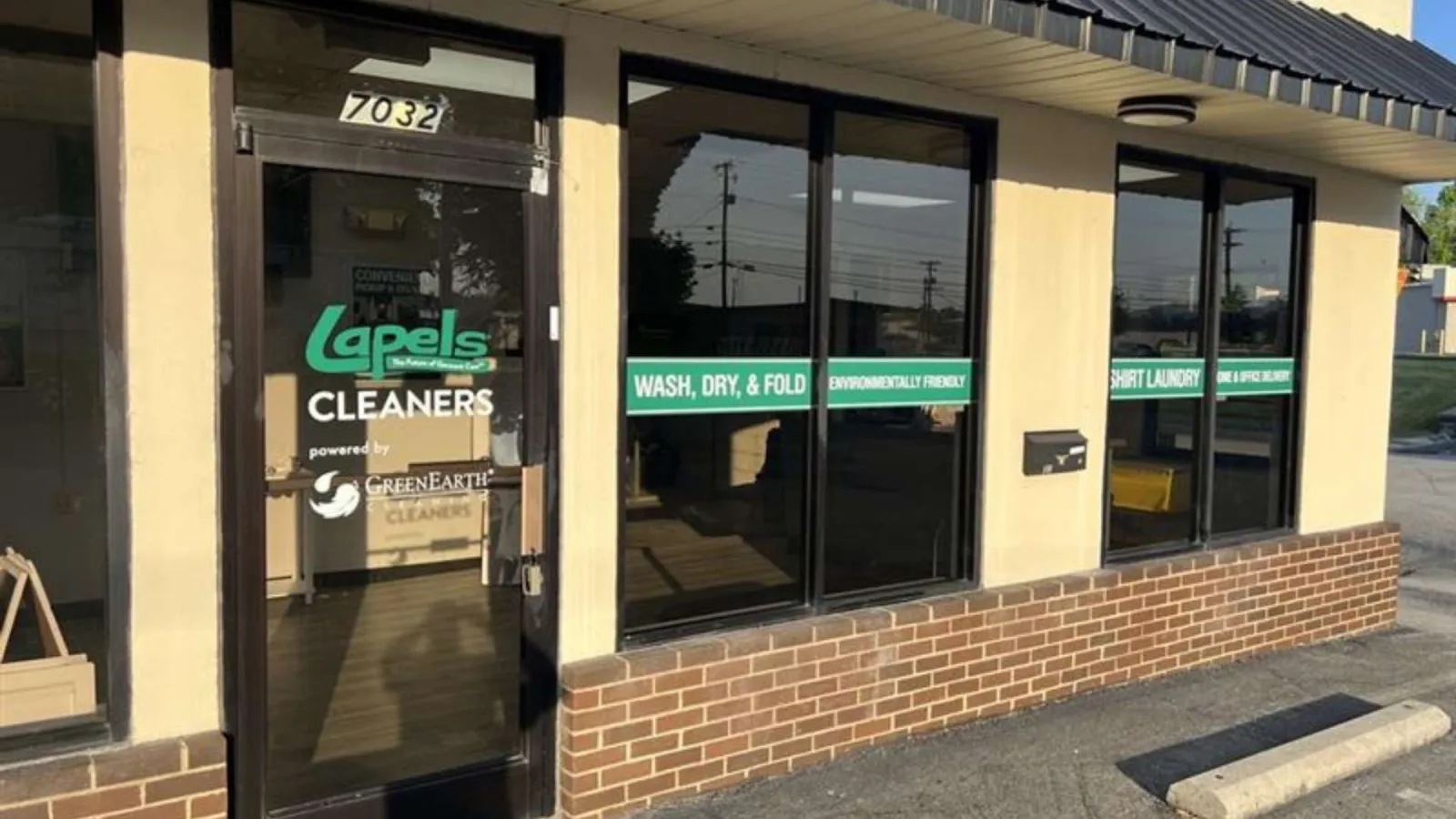Front entrance of Lapels Cleaners with large windows displaying wash, dry, fold, and environmentally friendly services.