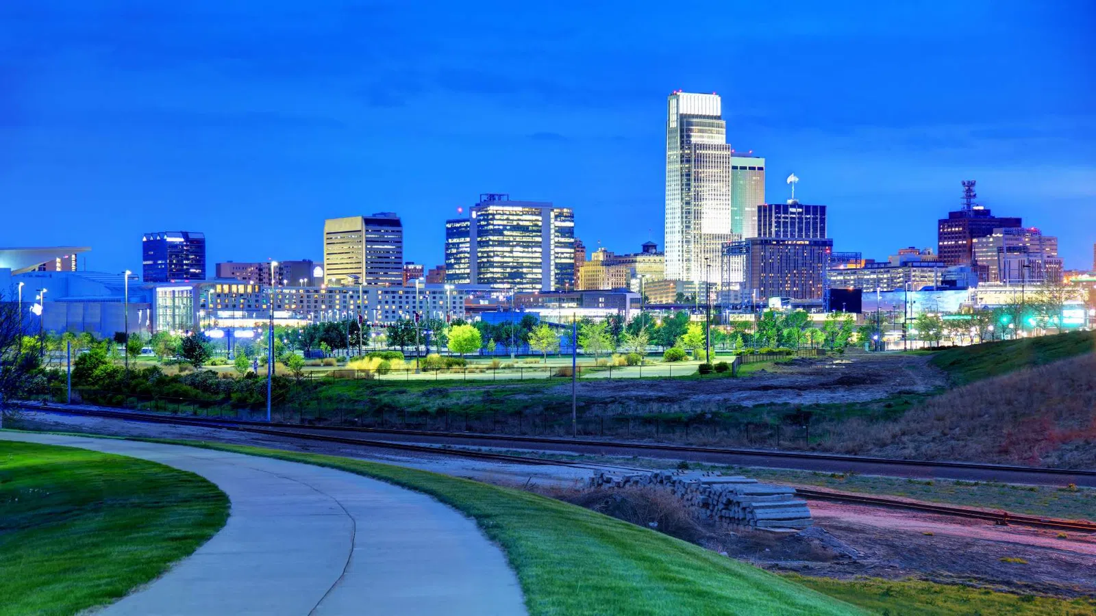 Aerial view of a Omaha featuring mixed-use buildings, greenery, and cloudy sky during daytime.