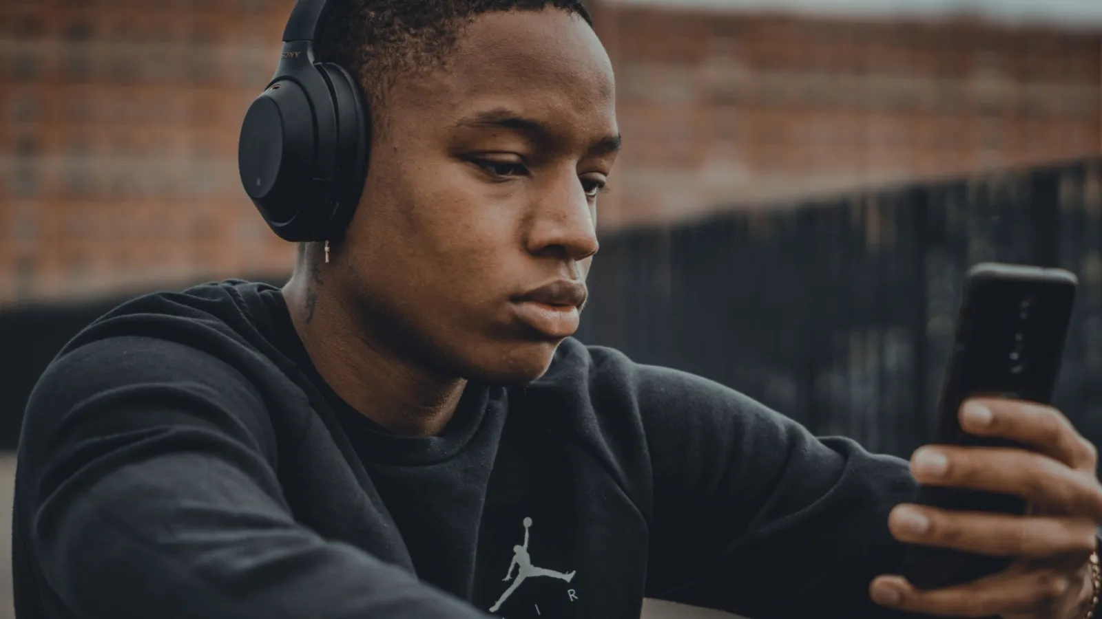 a man wearing headphones and holding a phone