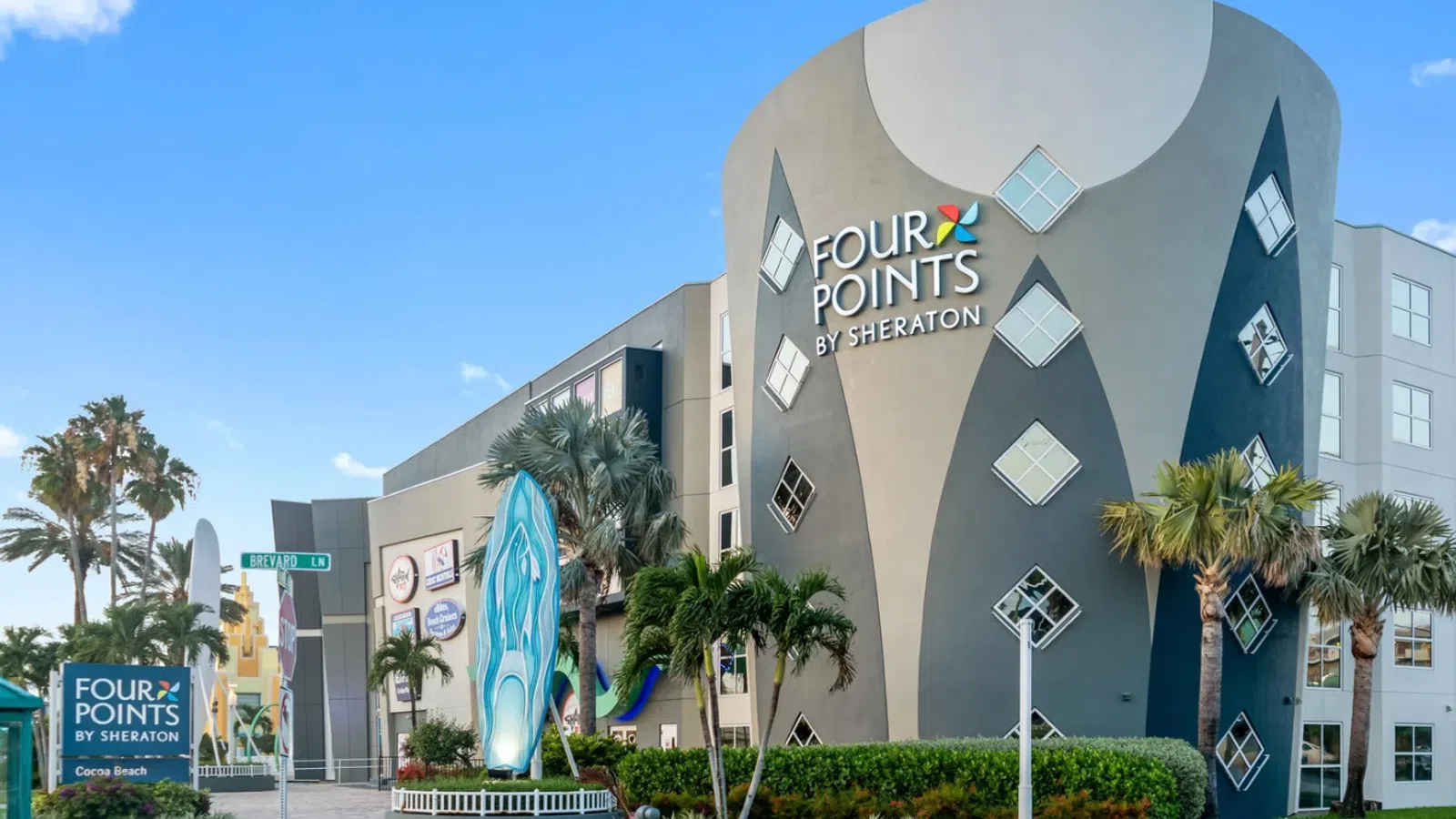 Four Points by Sheraton hotel building with palm trees and clear blue sky at Cocoa Beach