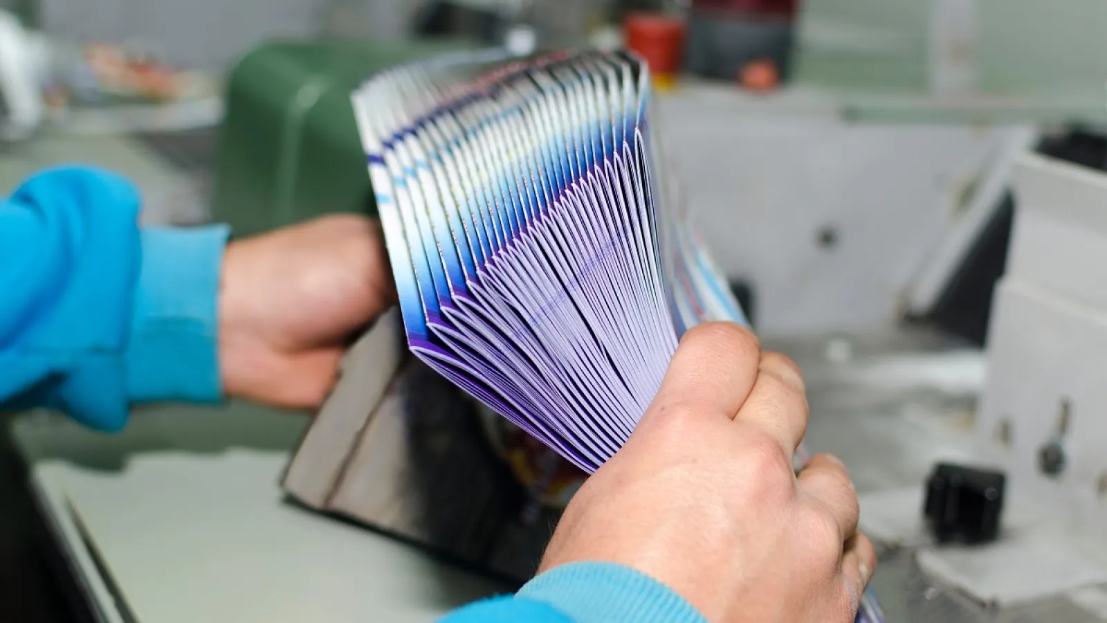 A person gathering a bundle of Printed and Folded Brochures
