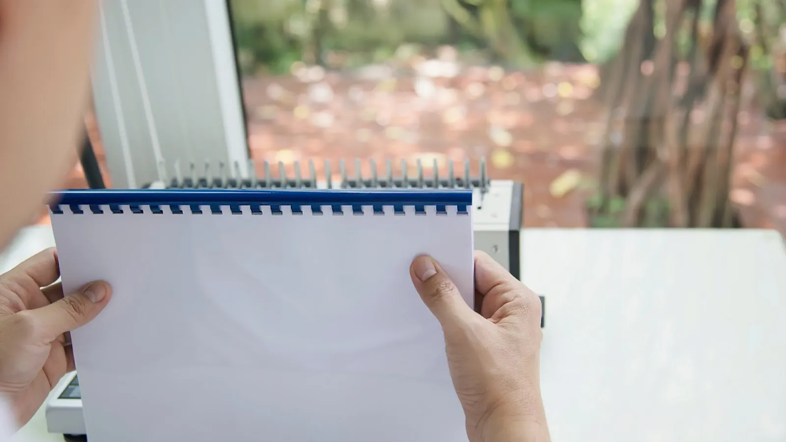 A person holding a Comb Bound Book