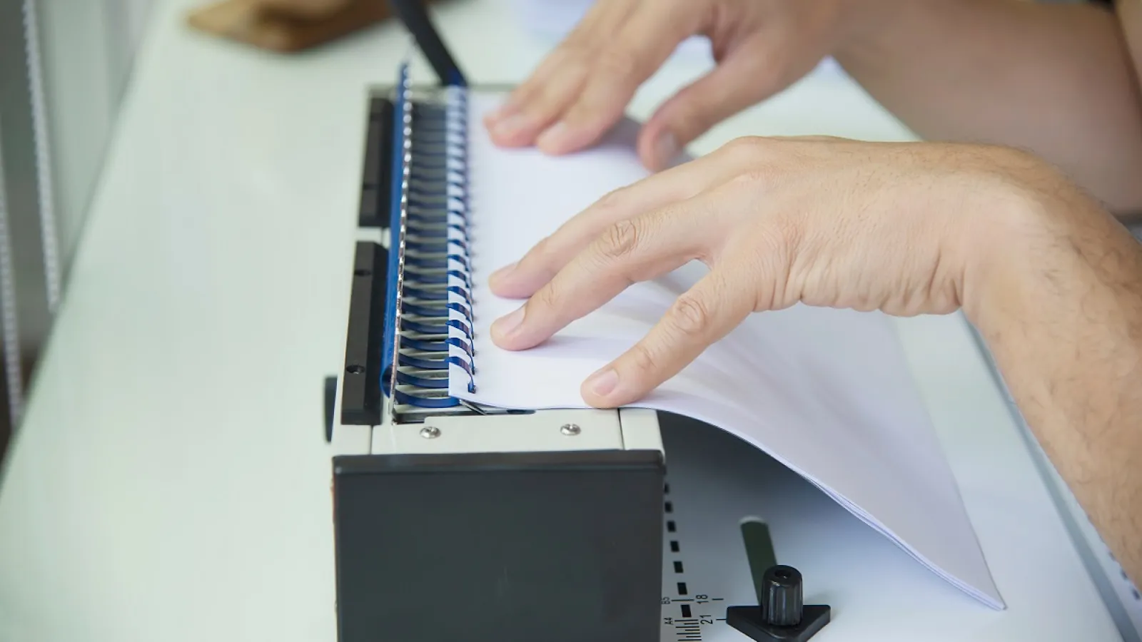 A person binding pages with a Plastic Binding Comb