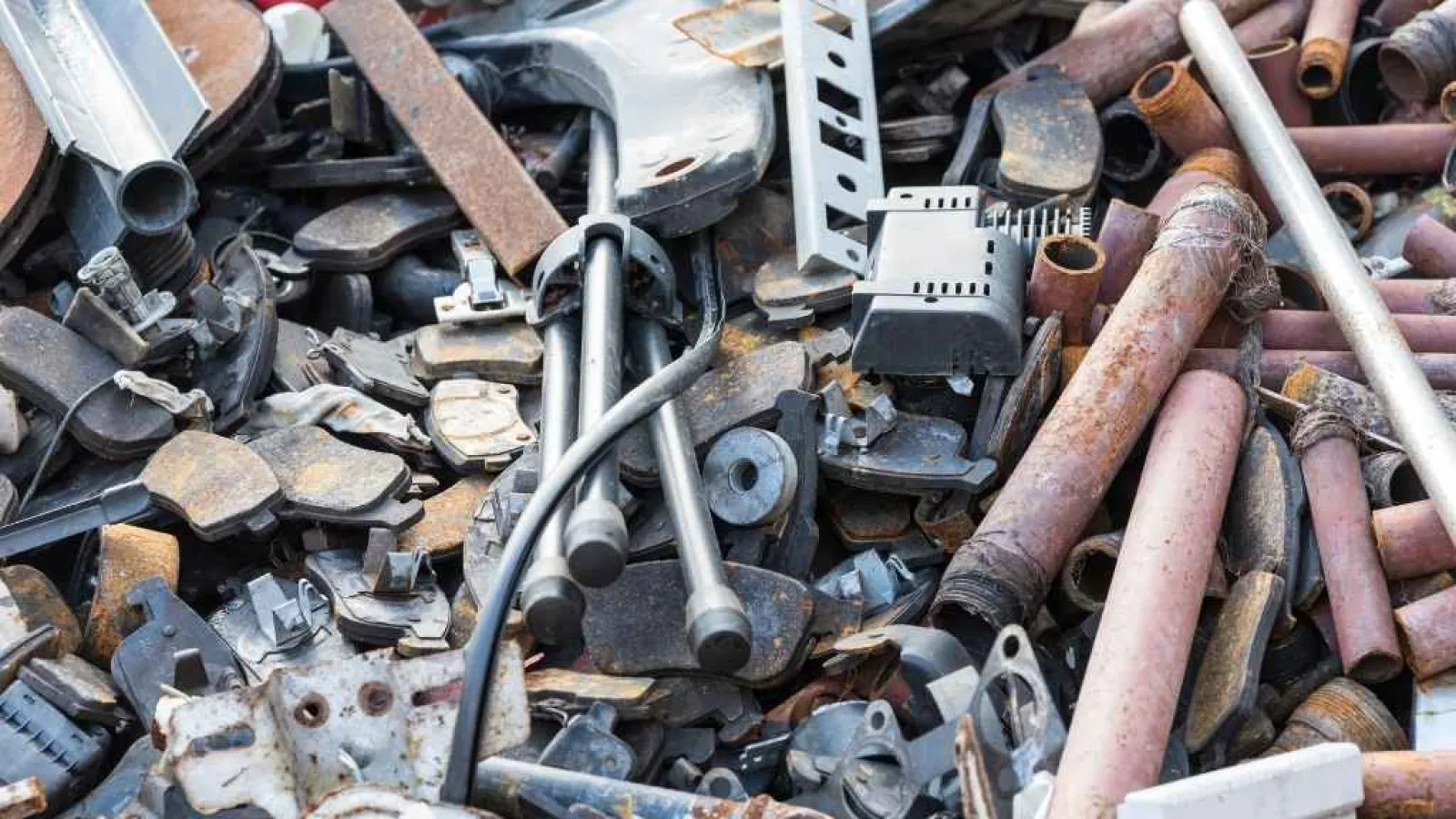 Pile of assorted rusty metal scrap and machine parts in a cluttered junkyard setting