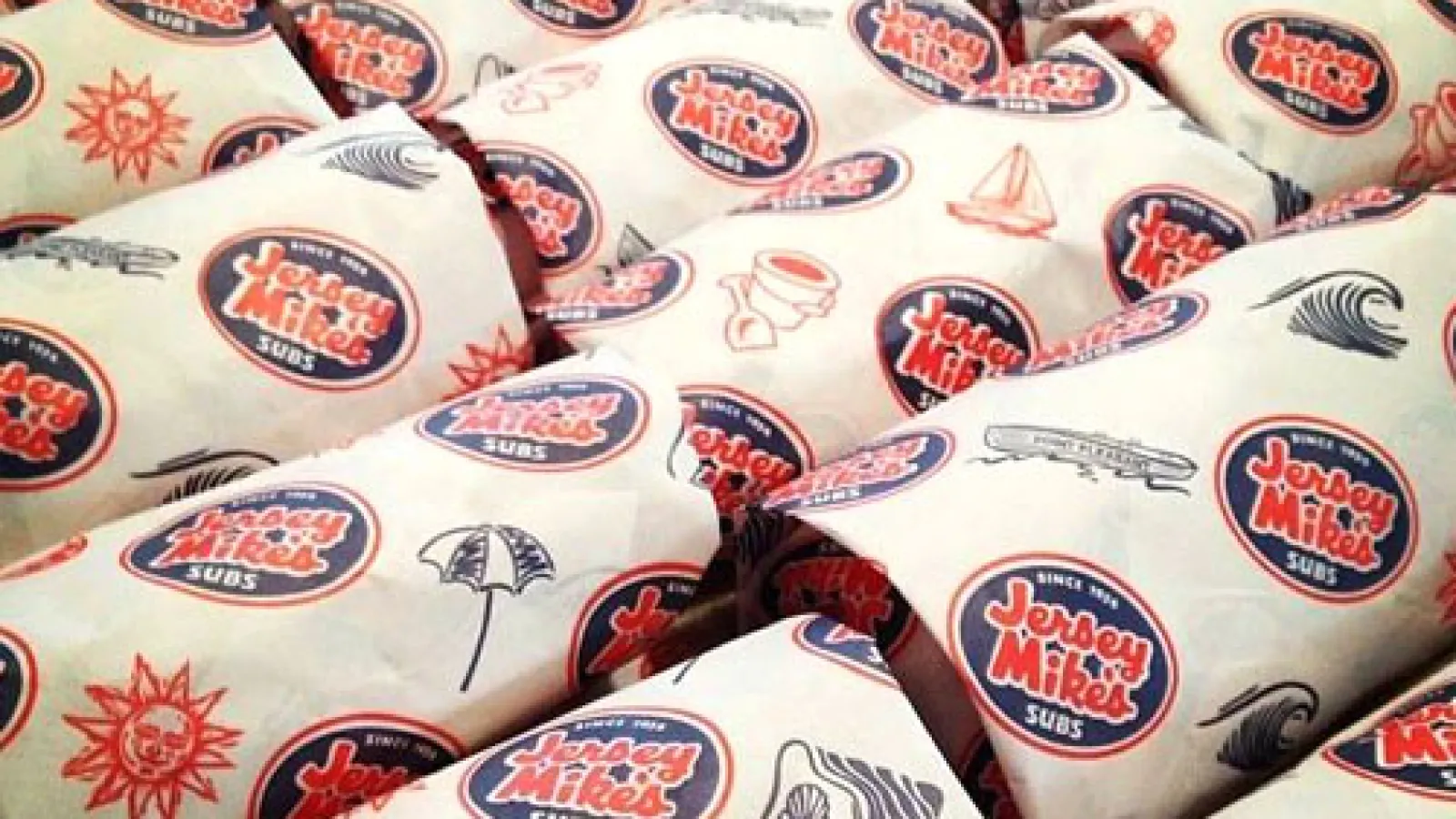 Multiple Jersey Mike's Subs wrapped in branded paper showing logo and beach-themed icons