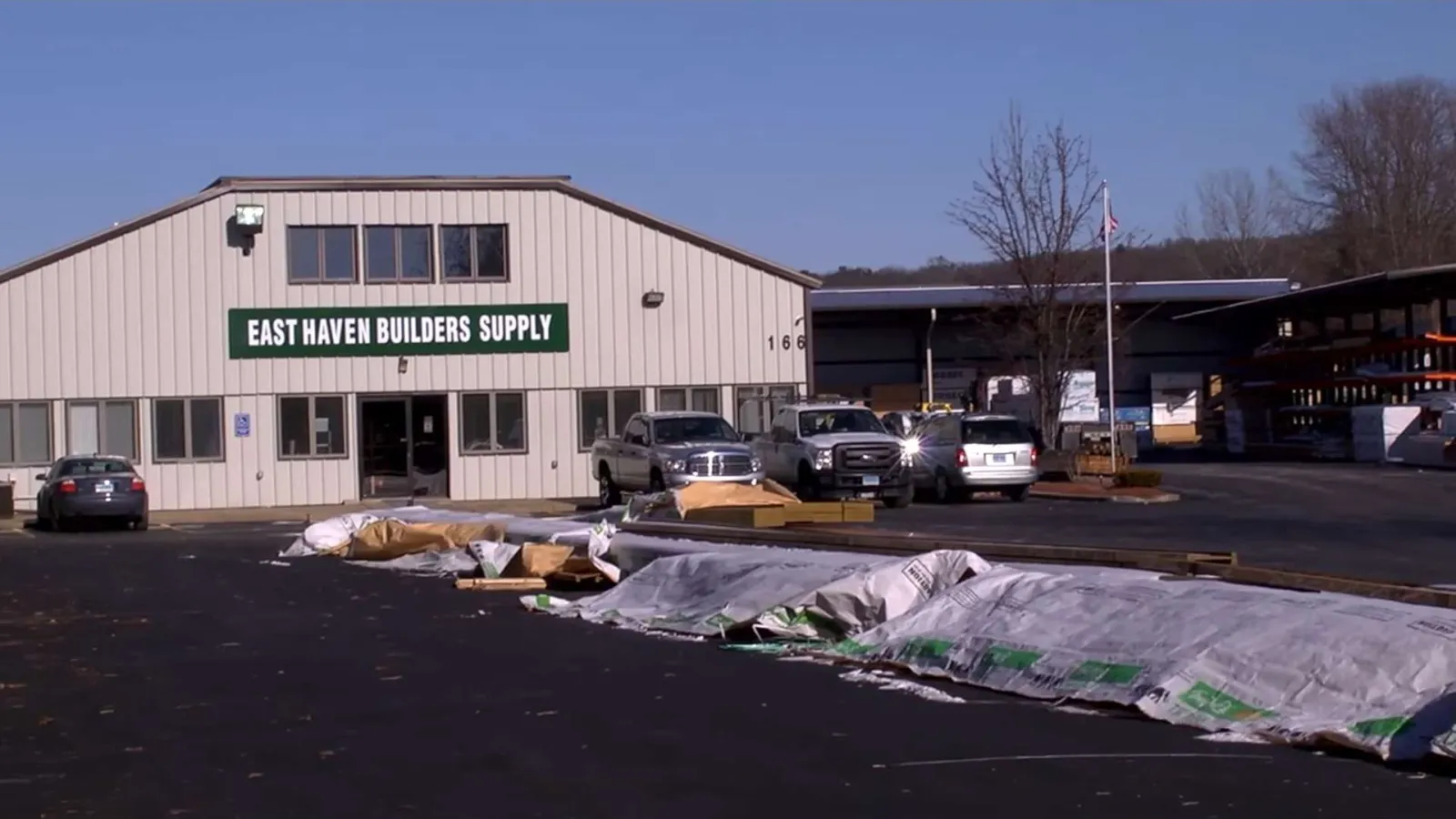 East Haven Builders Supply warehouse building with trucks and construction materials outside on asphalt lot