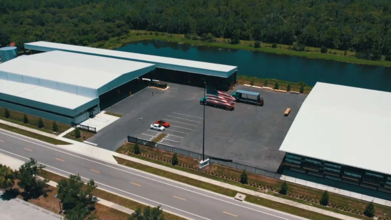 Dual monitors showing a Vimeo video of a lumberyard and a content management platform with editing tools.