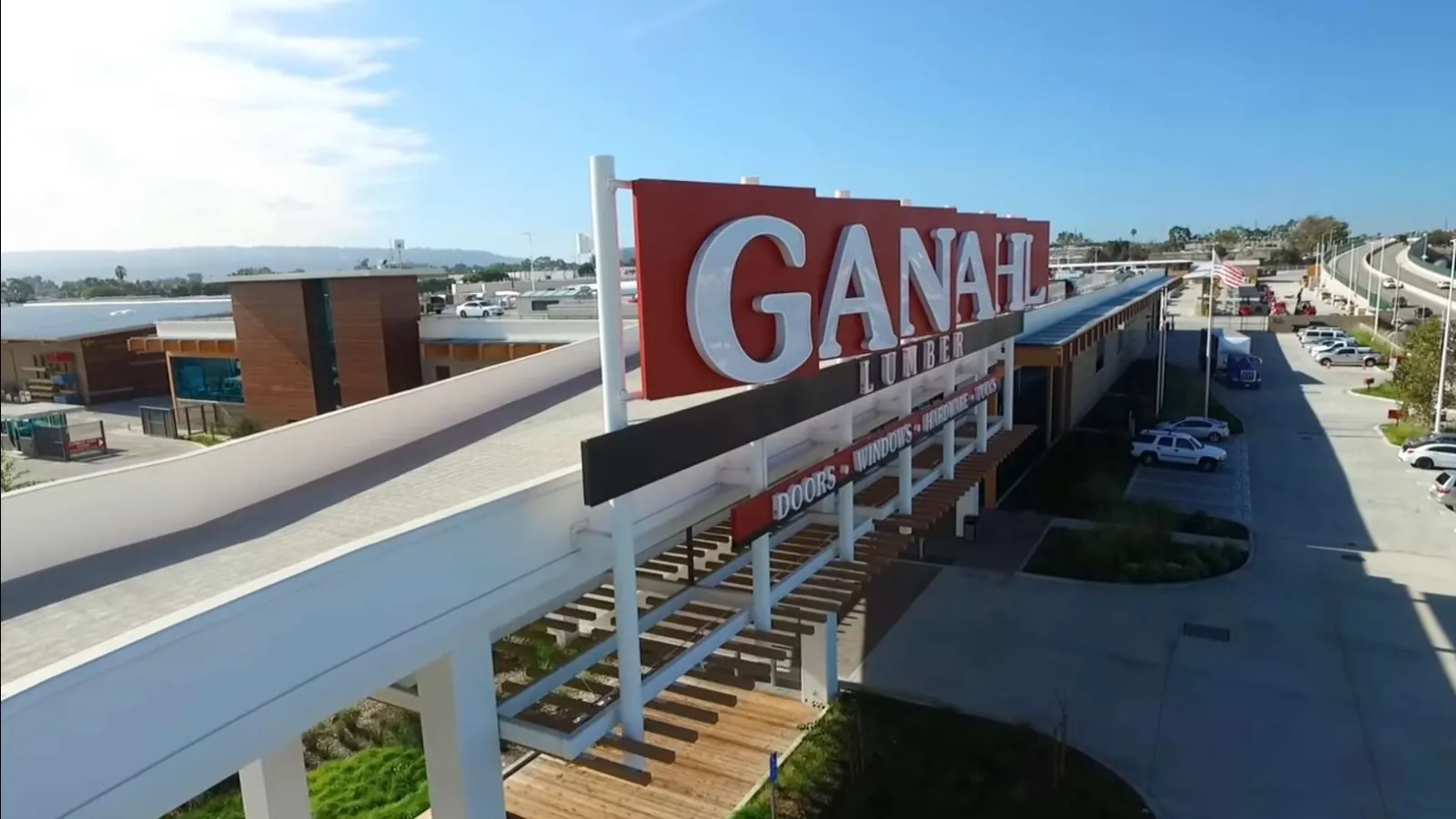 Outdoor view of Ganahl lumber exterior with clear blue sky and parking area under sunlight.