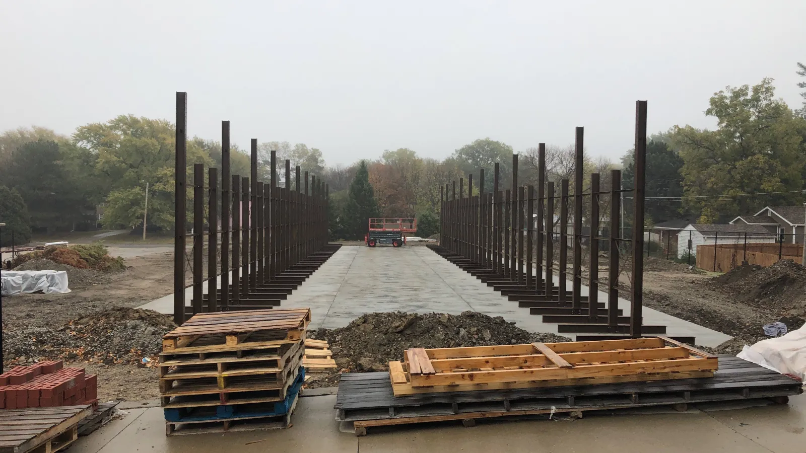Construction site with steel framework columns and concrete foundation in early building phase on a foggy day.