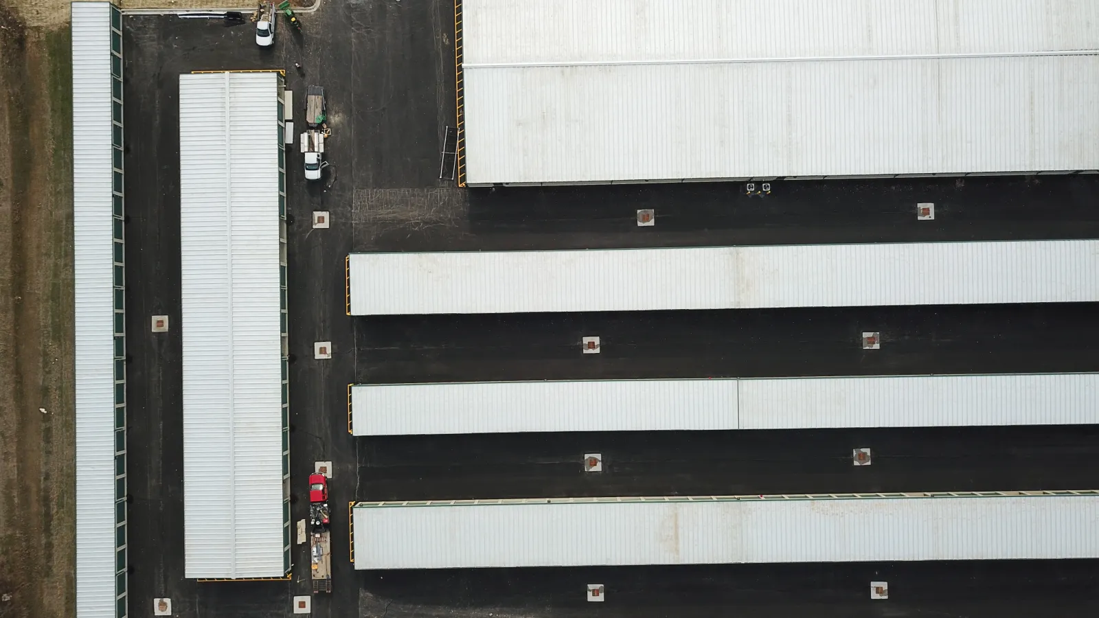 Aerial view of a large industrial warehouse complex with multiple white-roofed buildings and empty parking lots.