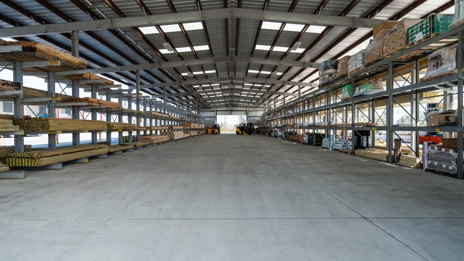 Spacious warehouse interior with metal shelving units stocked with construction materials and equipment.