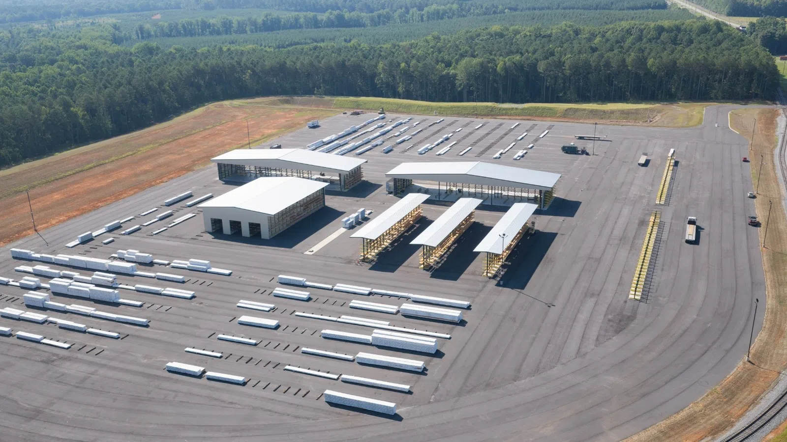 Aerial view of a large truck terminal with multiple semi-truck trailers parked and warehouse buildings in a rural area.