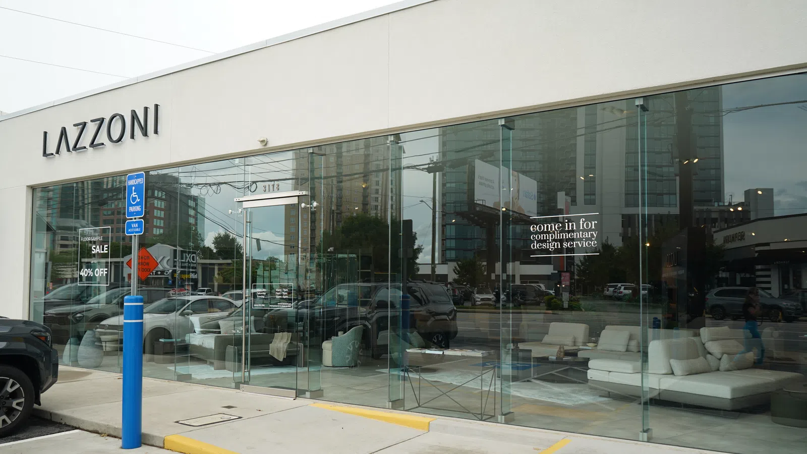 Modern Lazzoni furniture store with glass facade showcasing white sofas and complimentary design service offer.