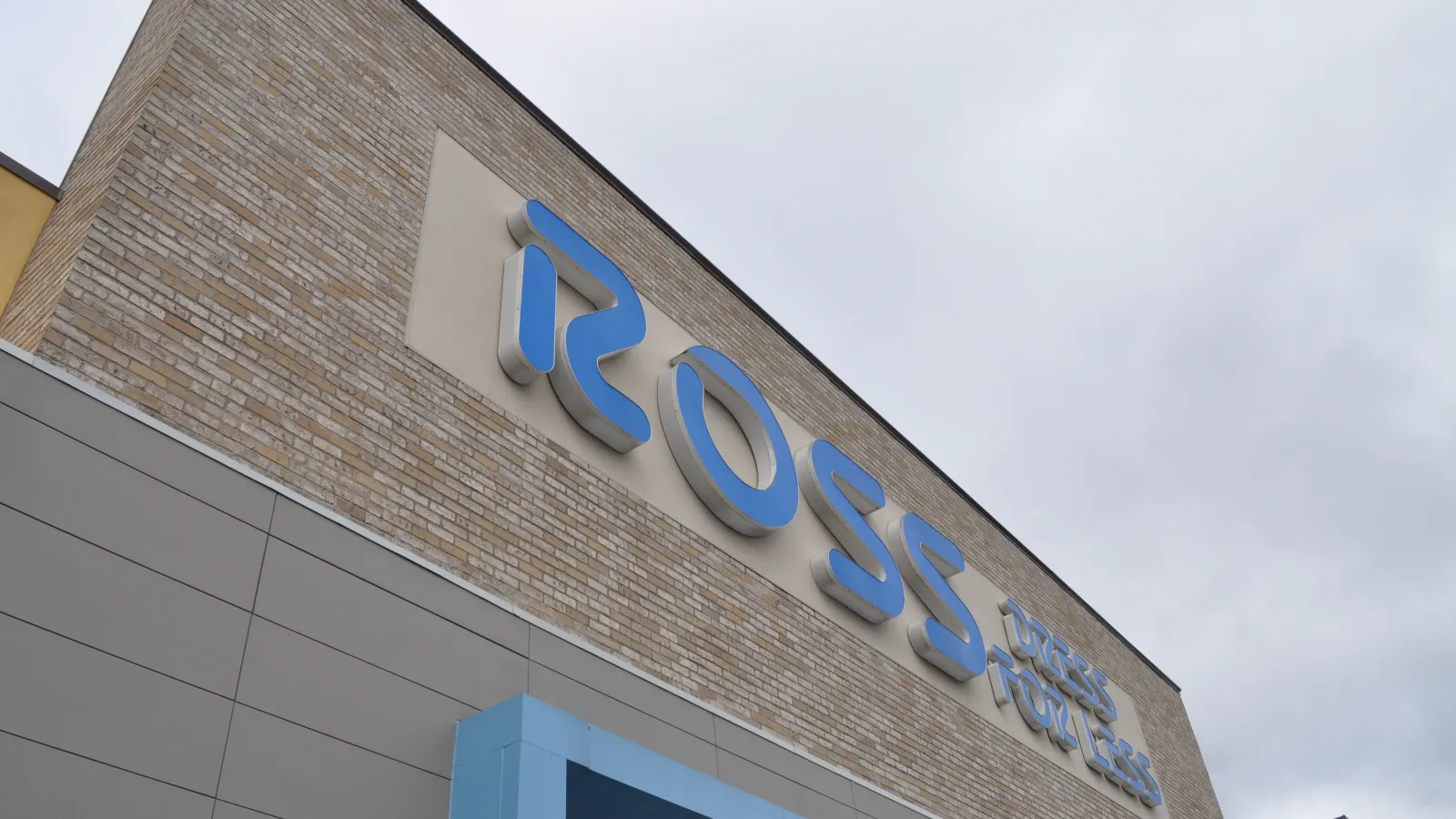Blue Ross Dress for Less sign on a brick and gray store exterior under cloudy sky.