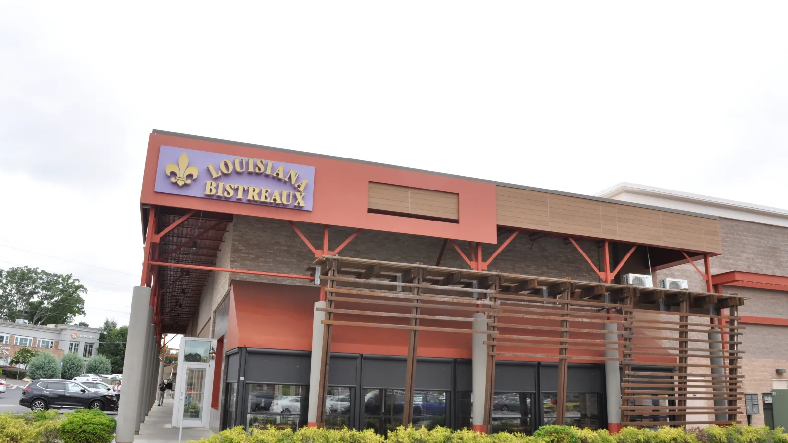 Exterior view of Louisiana Bistreaux restaurant with red and brown facade and wooden pergola structure.