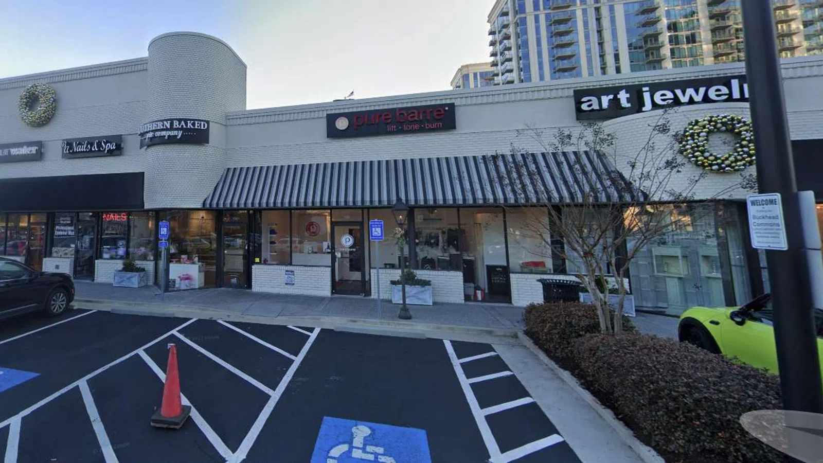 Strip mall with businesses including a spa, bakery, nail salon, and art jewelry shop with handicapped parking.