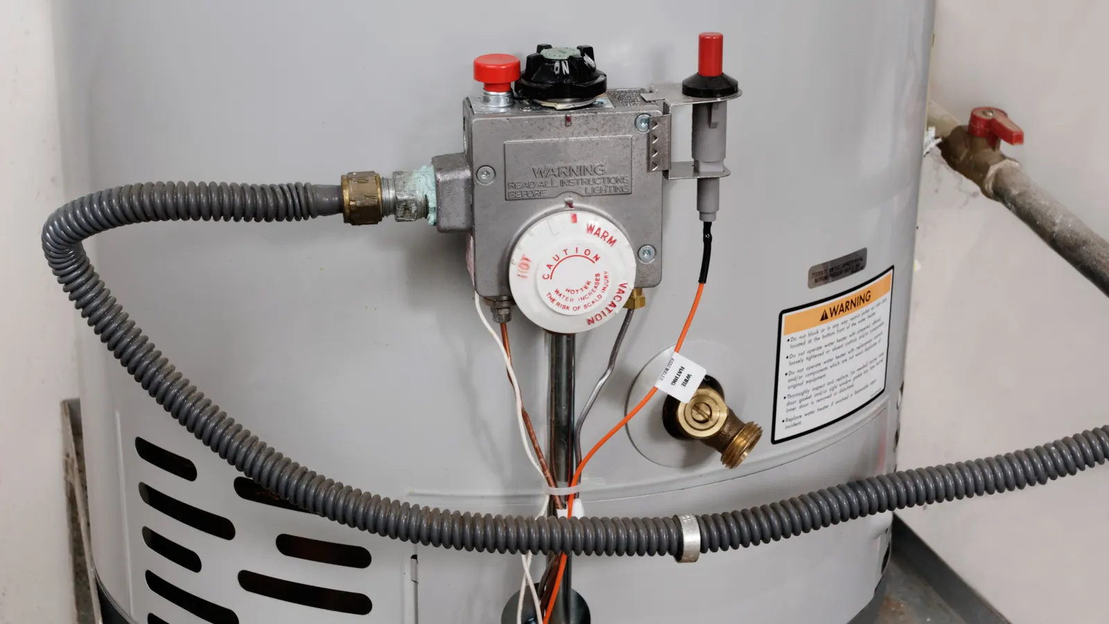 Close-up of a water heater with plumbing and safety features clearly visible.