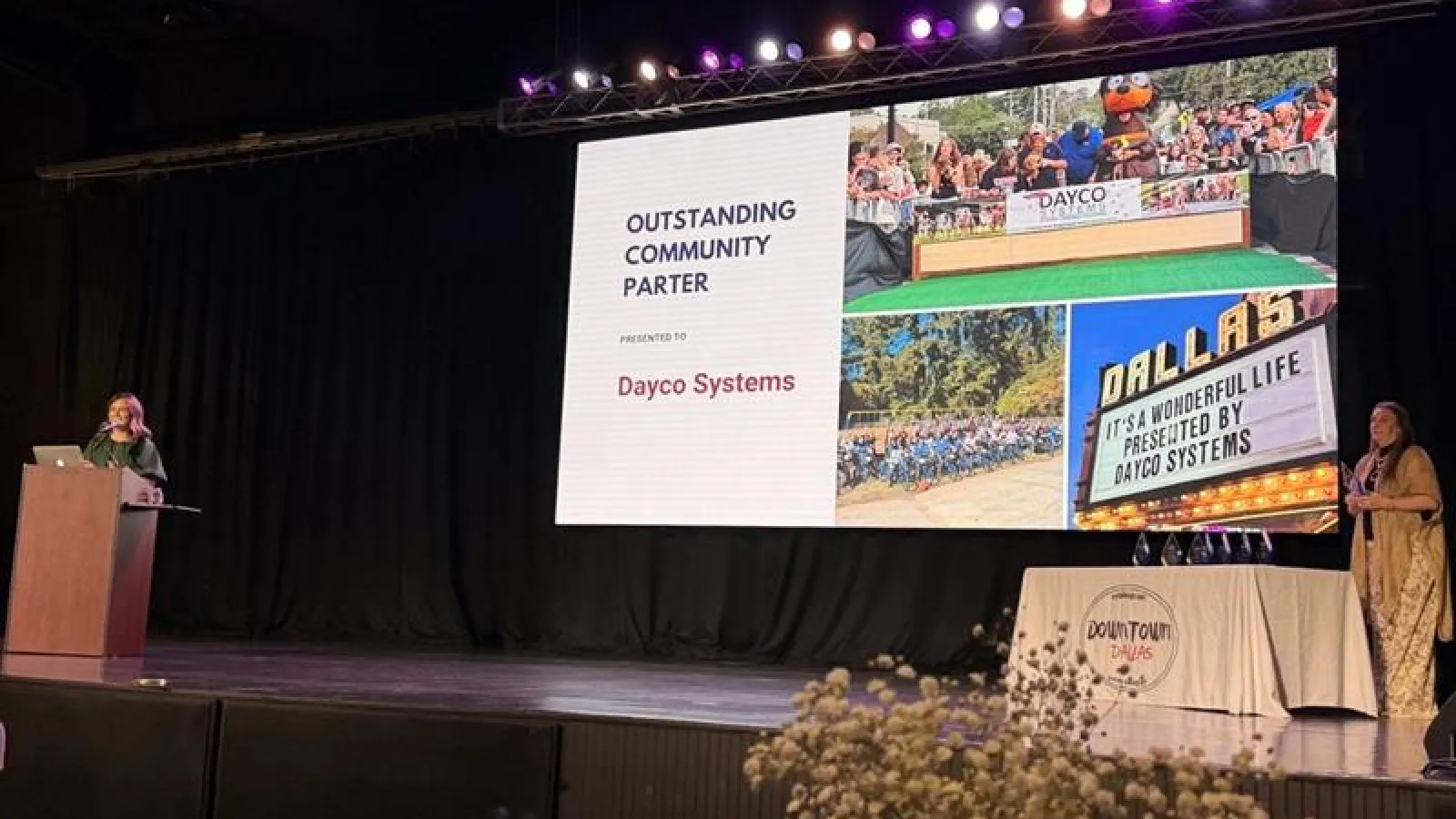 Award presentation on stage honoring Dayco Systems as Outstanding Community Partner with a large screen display.