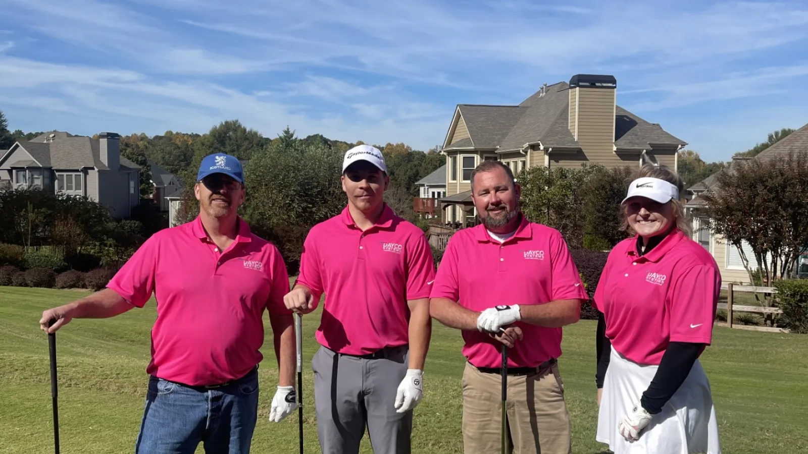 a group of people wearing pink shirts and holding golf clubs