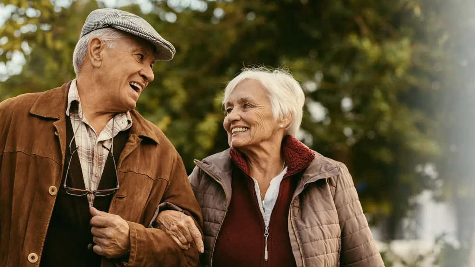 Happy elderly couple walking outdoors arm in arm enjoying nature and each other's company